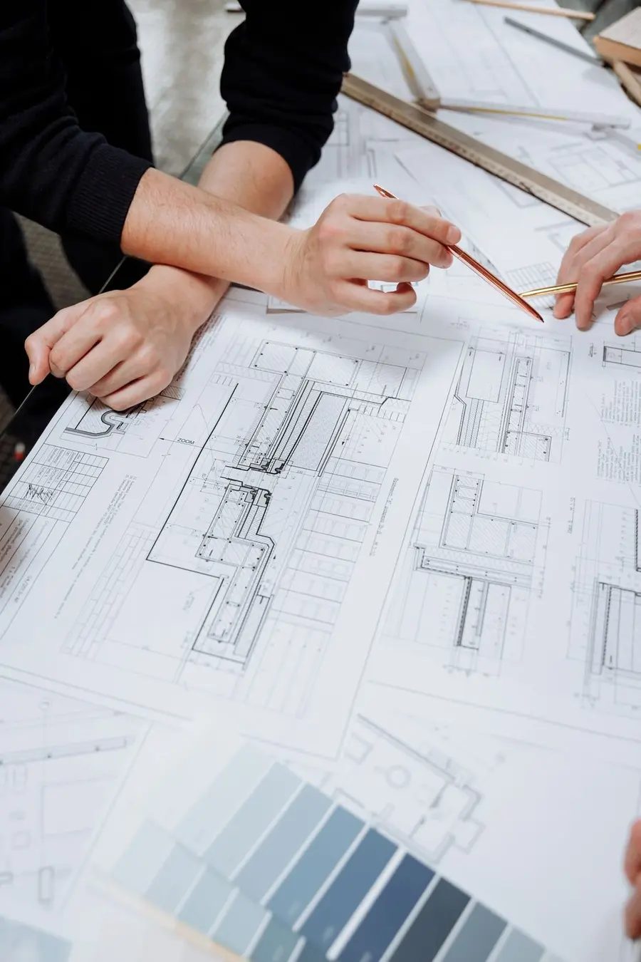 Two people marking up a facade detail sheet with a ruler and pencil