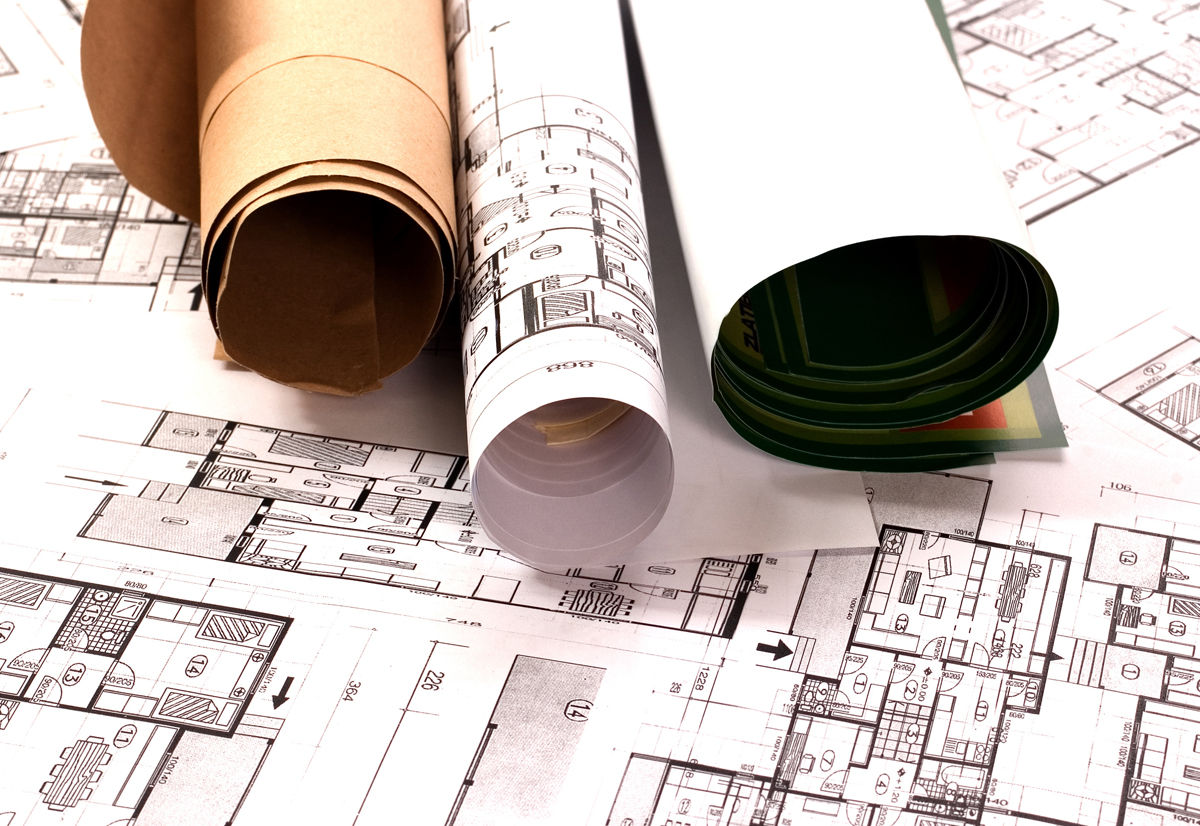 Rolled construction blueprints and color swatches spread across engineering floor plans