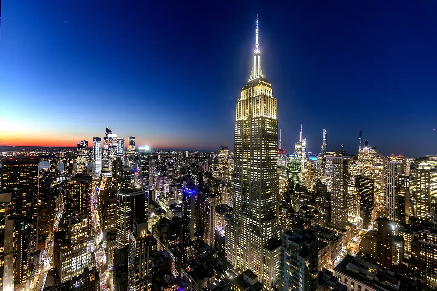 The Empire State Building illuminated against the New York City skyline at dusk